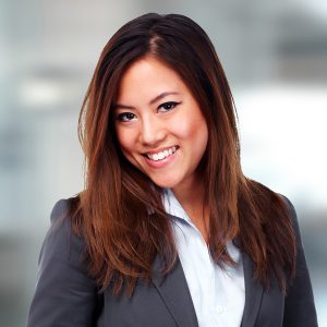 A photo of an Asian woman with brown hair facing sideways and smiling